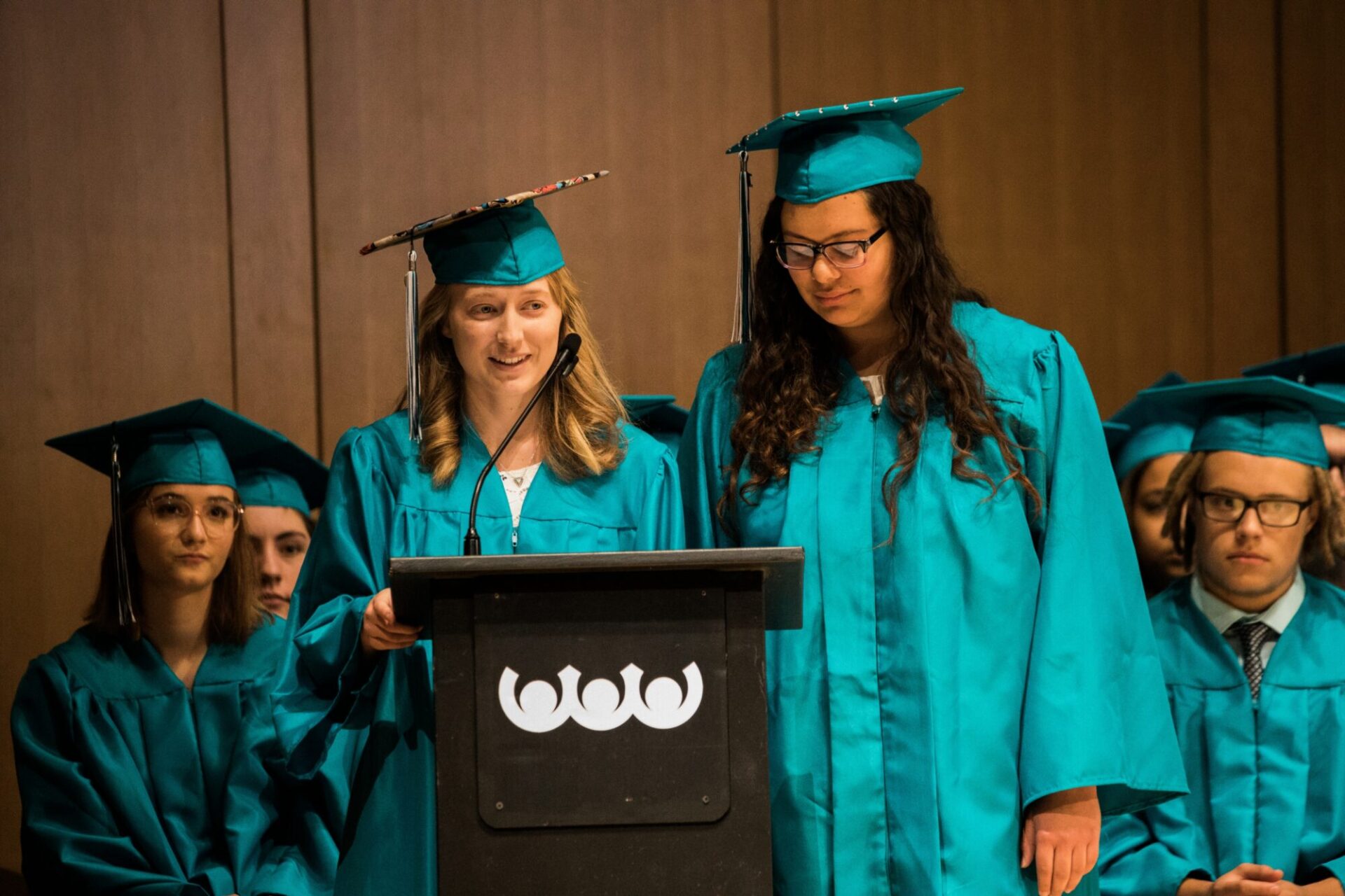 Graduates speaking at a lectern in front of the audience